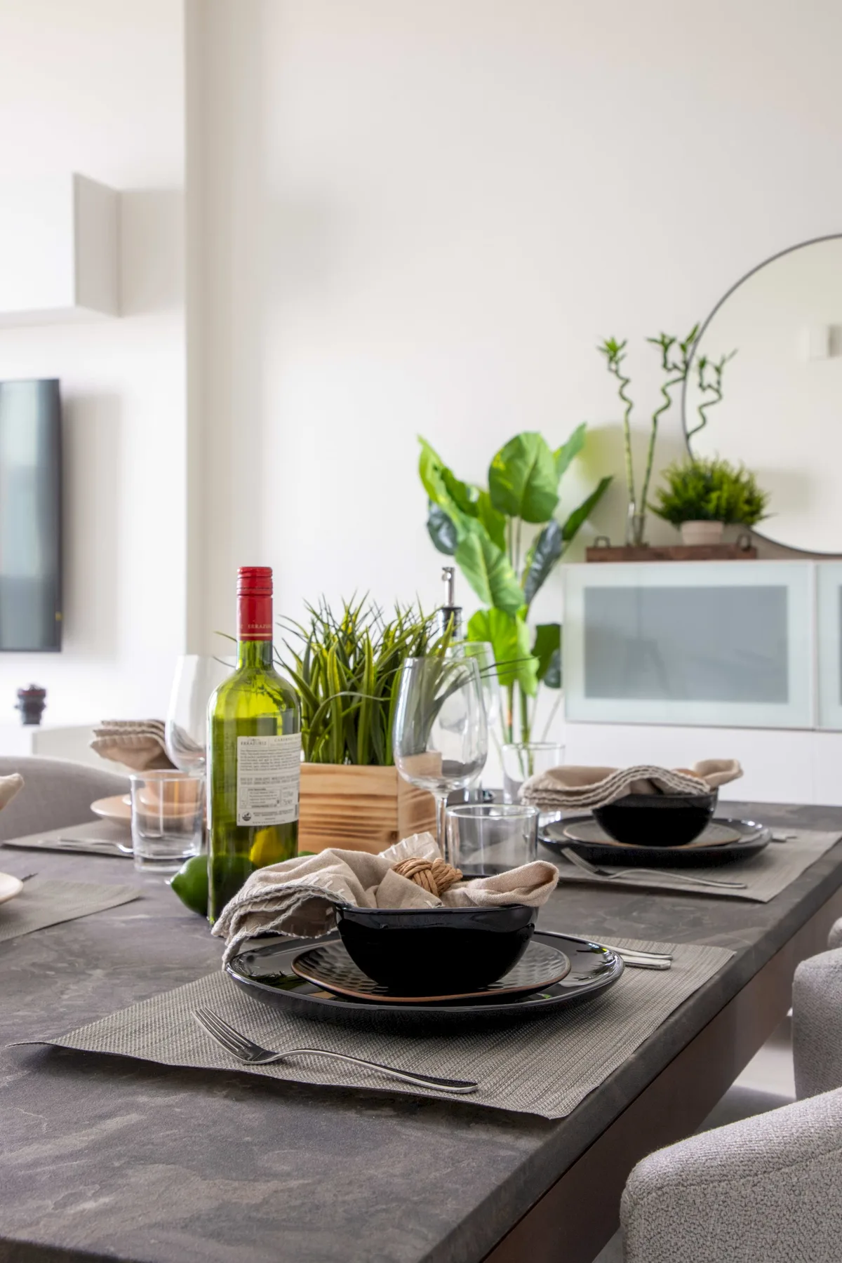 A dining table is set with dishes and wine in a bright dining area.
