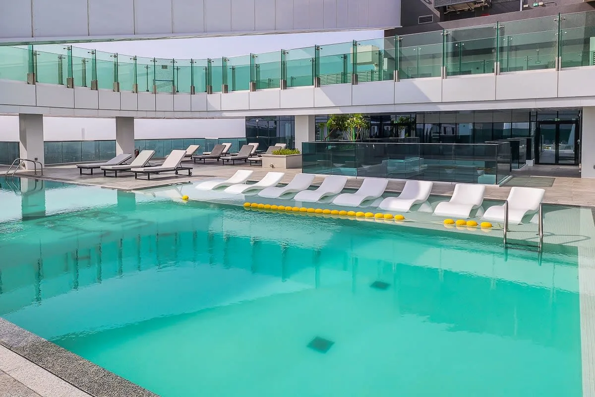 An outdoor swimming pool with submerged loungers beside a modern building.