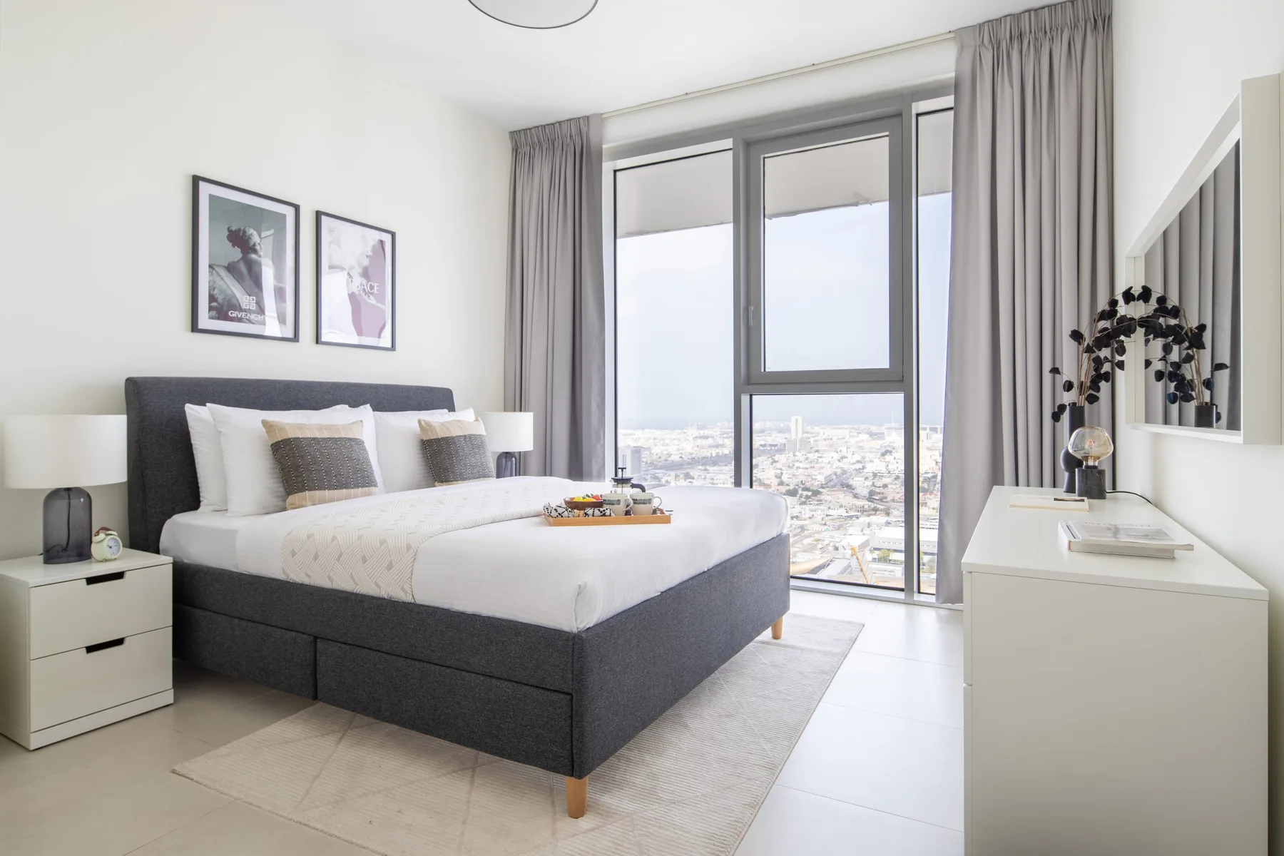A bedroom with a large bed beside a window overlooking the city.