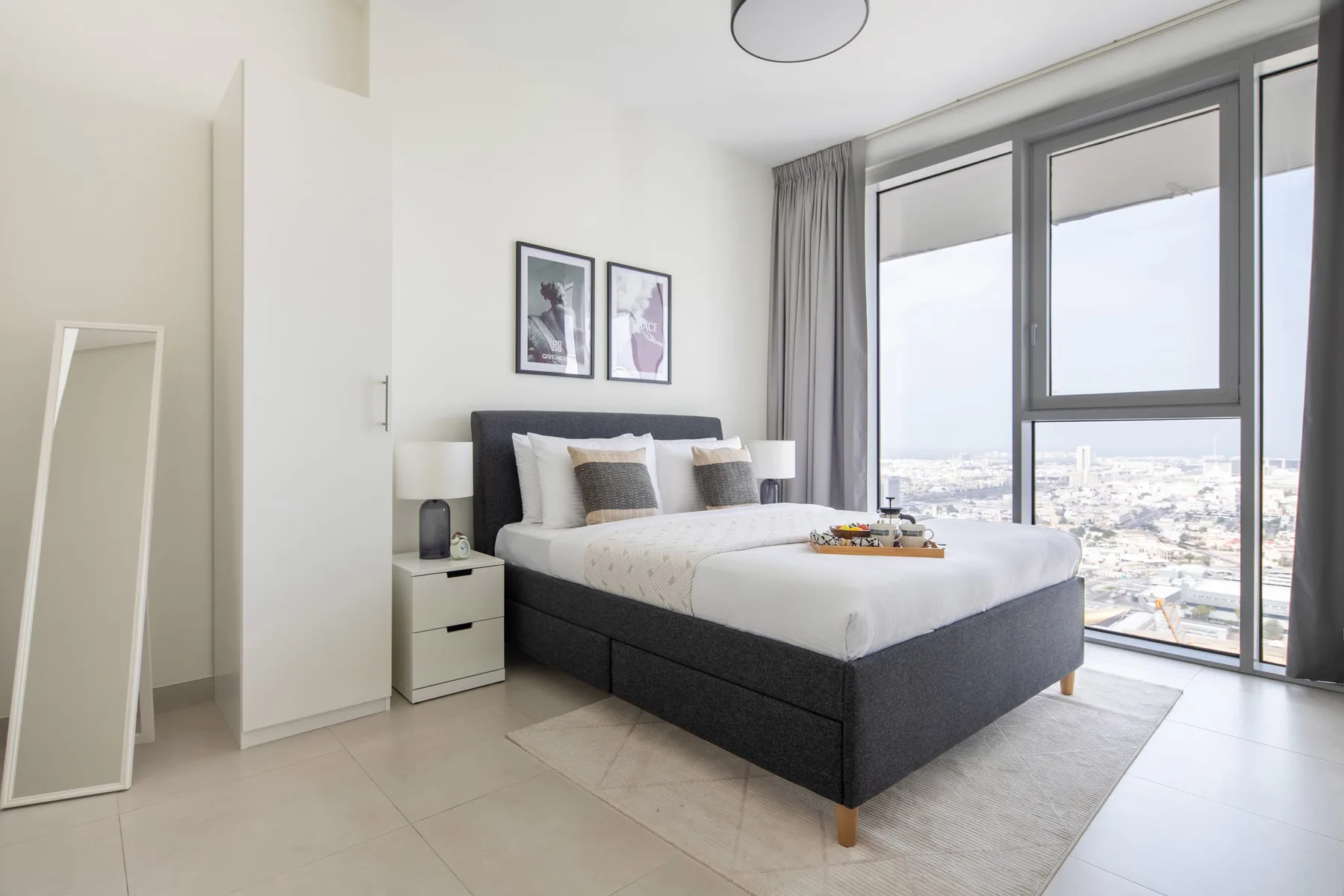A bright bedroom with a neatly made bed beside large windows.
