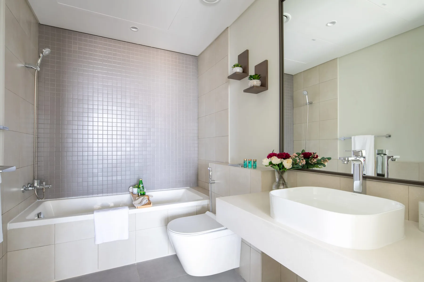 A bright bathroom with a bathtub, toilet, and wide vanity.