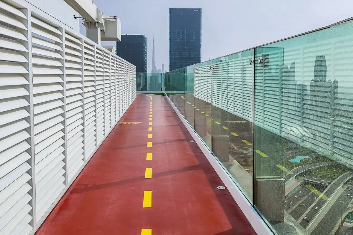 A red rooftop walkway runs between white slatted panels and glass railings.