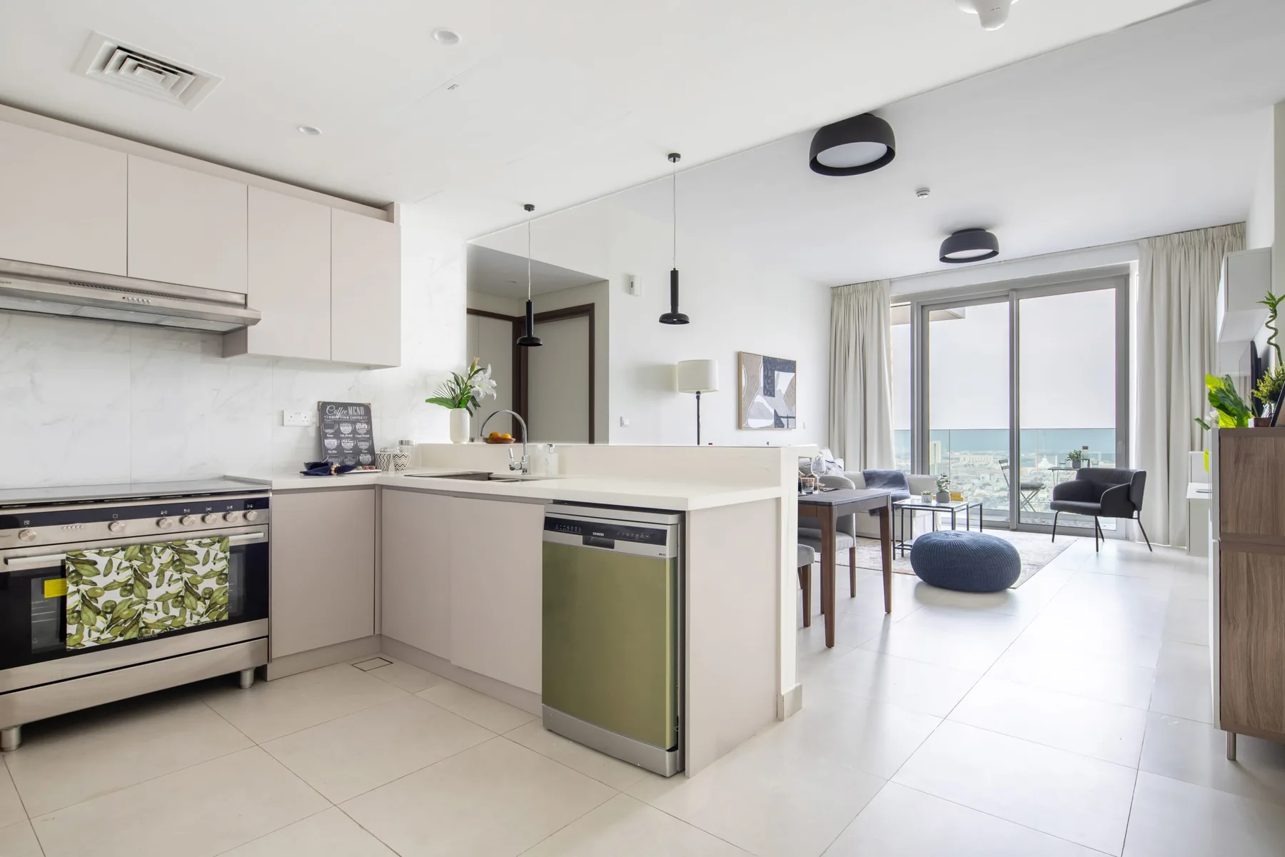 An open-plan kitchen and dining area opens onto a bright seating area by the windows.