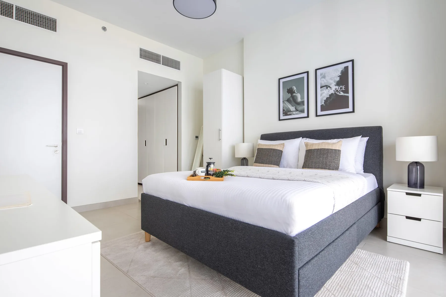 A bright bedroom with a large bed, bedside tables, and framed artwork.