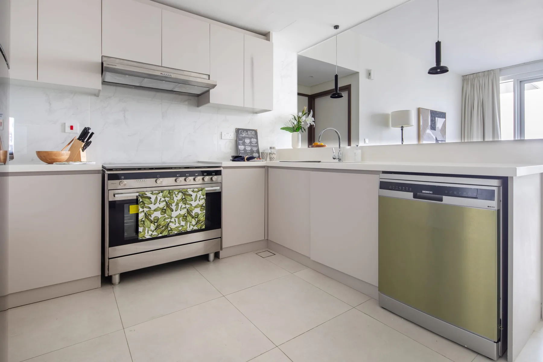 A bright kitchen with pale cabinetry, an oven, and a countertop sink.