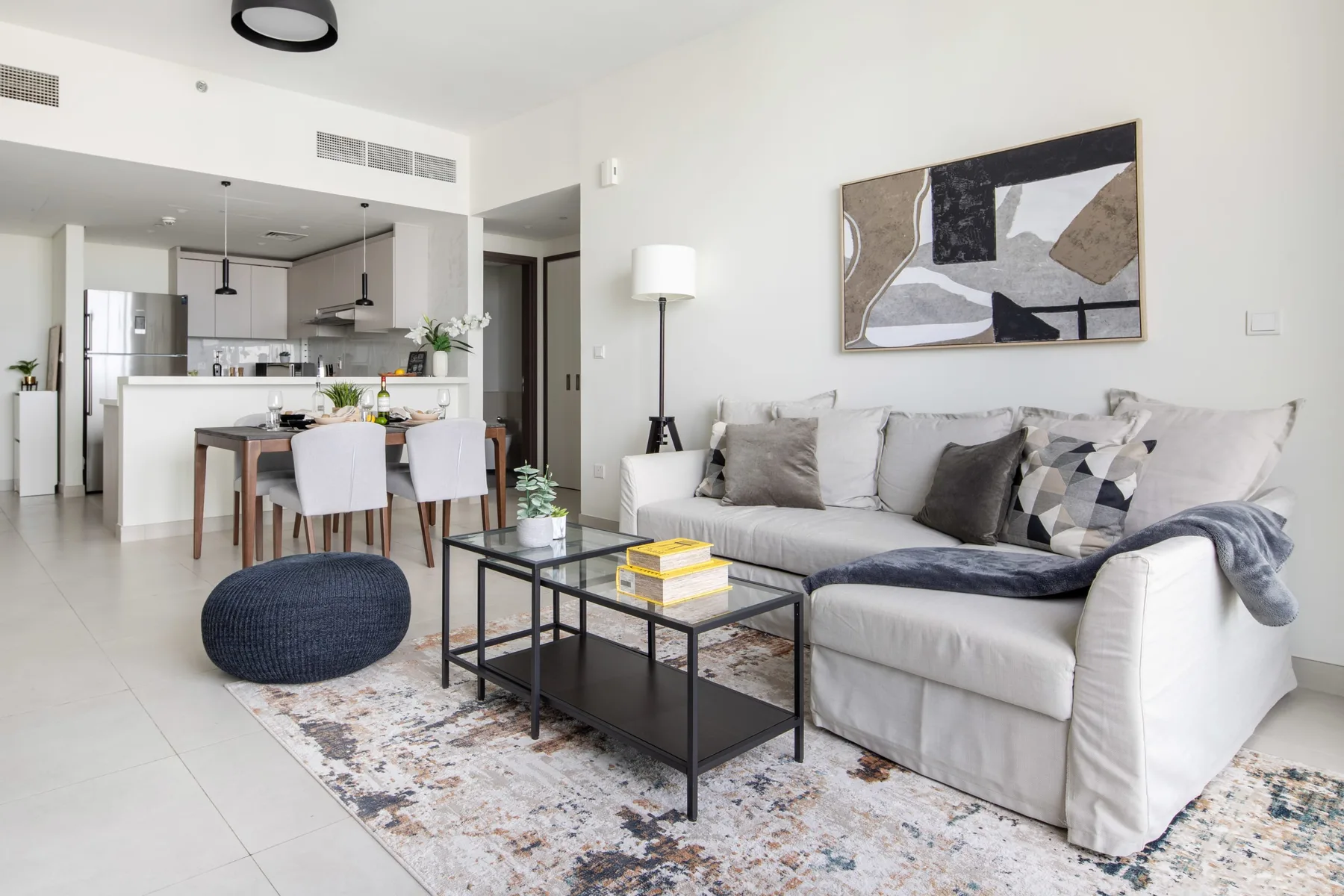 A bright living room with a sofa, coffee table, and open kitchen behind it.