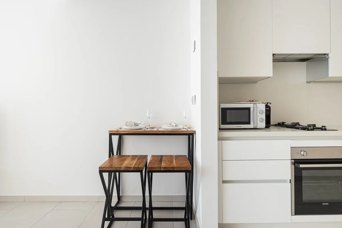 Una cocina compacta con una mesa y dos taburetes junto a la zona de cocción.