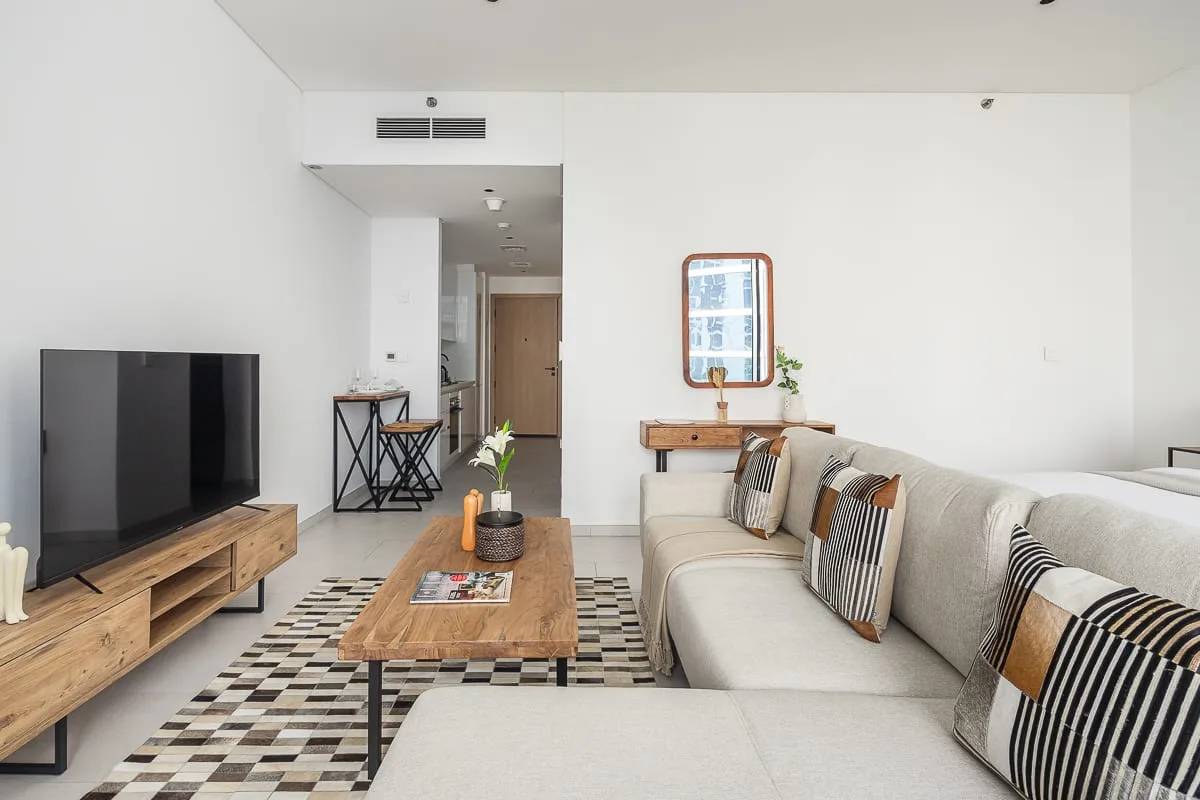 Una sala luminosa con televisor, mesa de centro y sofá largo.