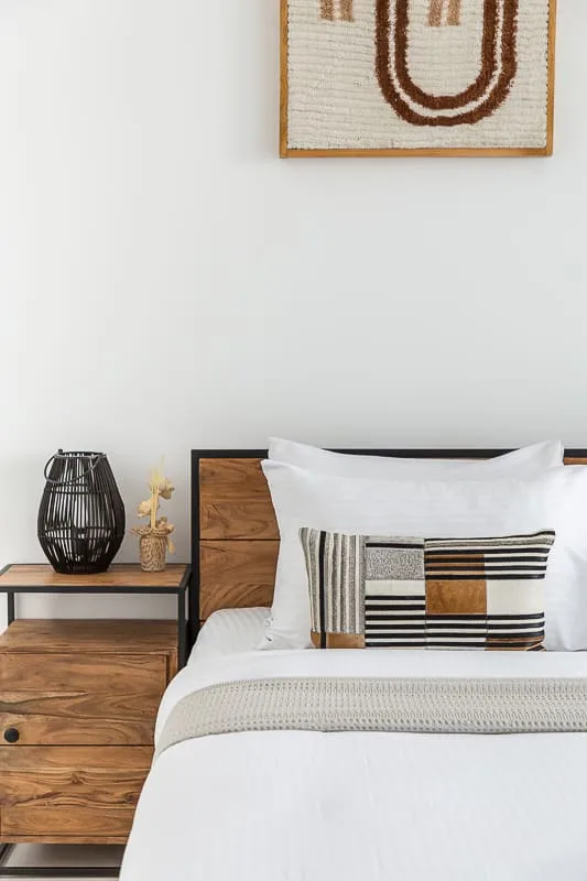 Un dormitorio con ropa de cama blanca y una mesita de madera.