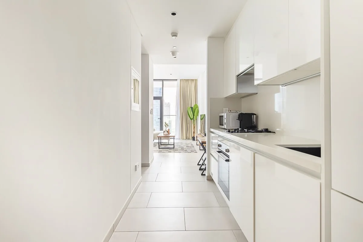 Una cocina luminosa y estrecha se abre a una sala con una ventana amplia.
