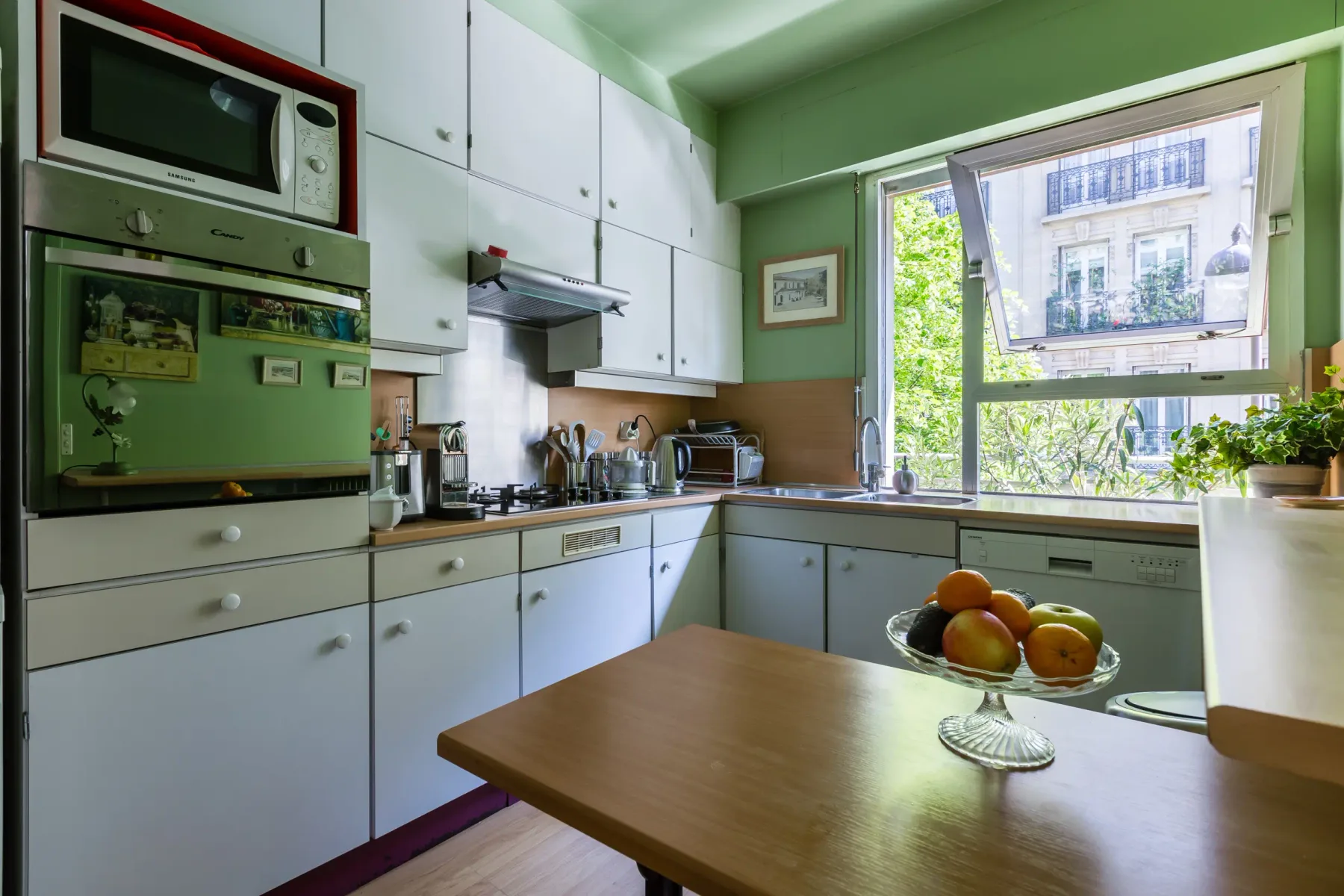 Una cocina colorida con gabinetes blancos, una zona de cocción y una ventana amplia.