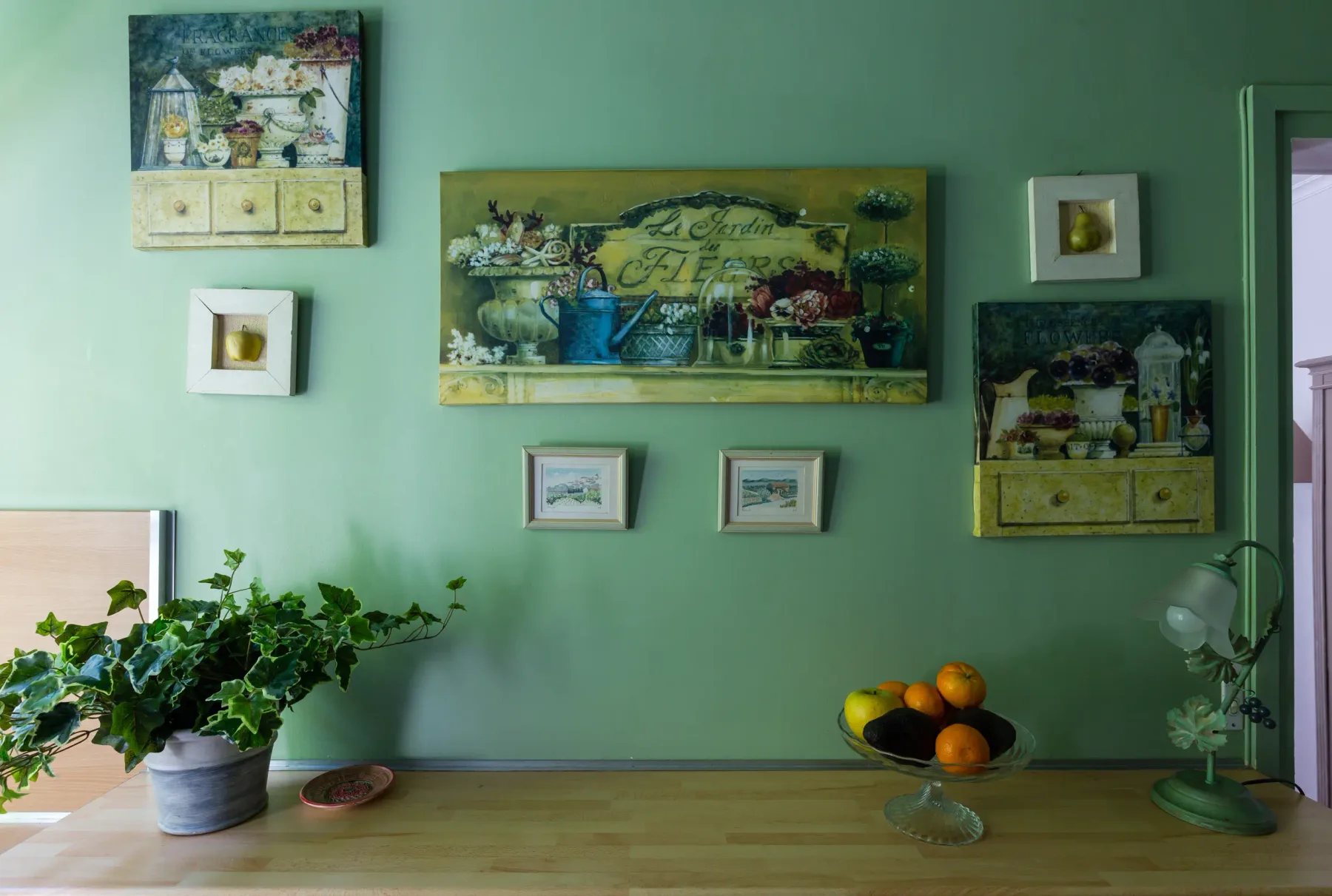 Una habitación colorida con cuadros de bodegones en una pared verde.