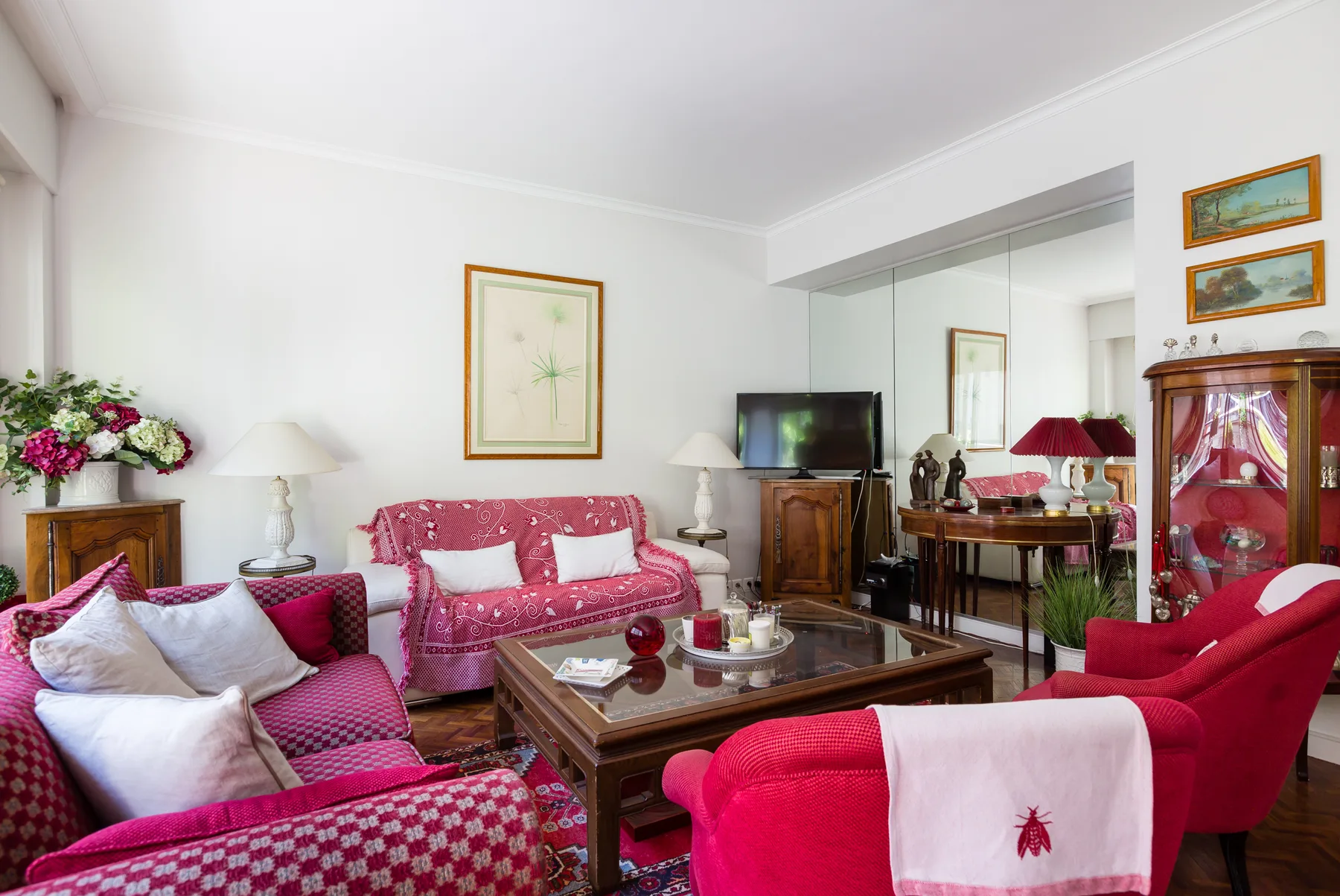 Una sala de estar con asientos estampados, una mesa de centro de madera y un televisor.