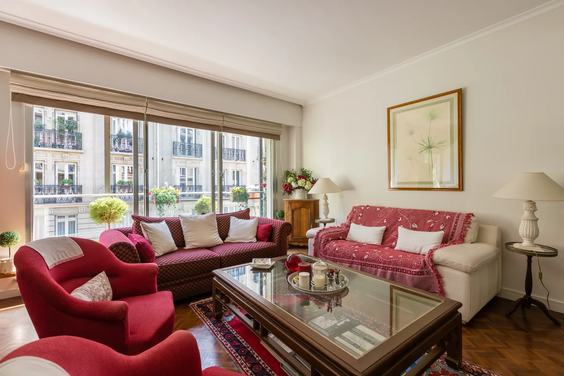 Living room with red seating, a glass coffee table, and large windows.