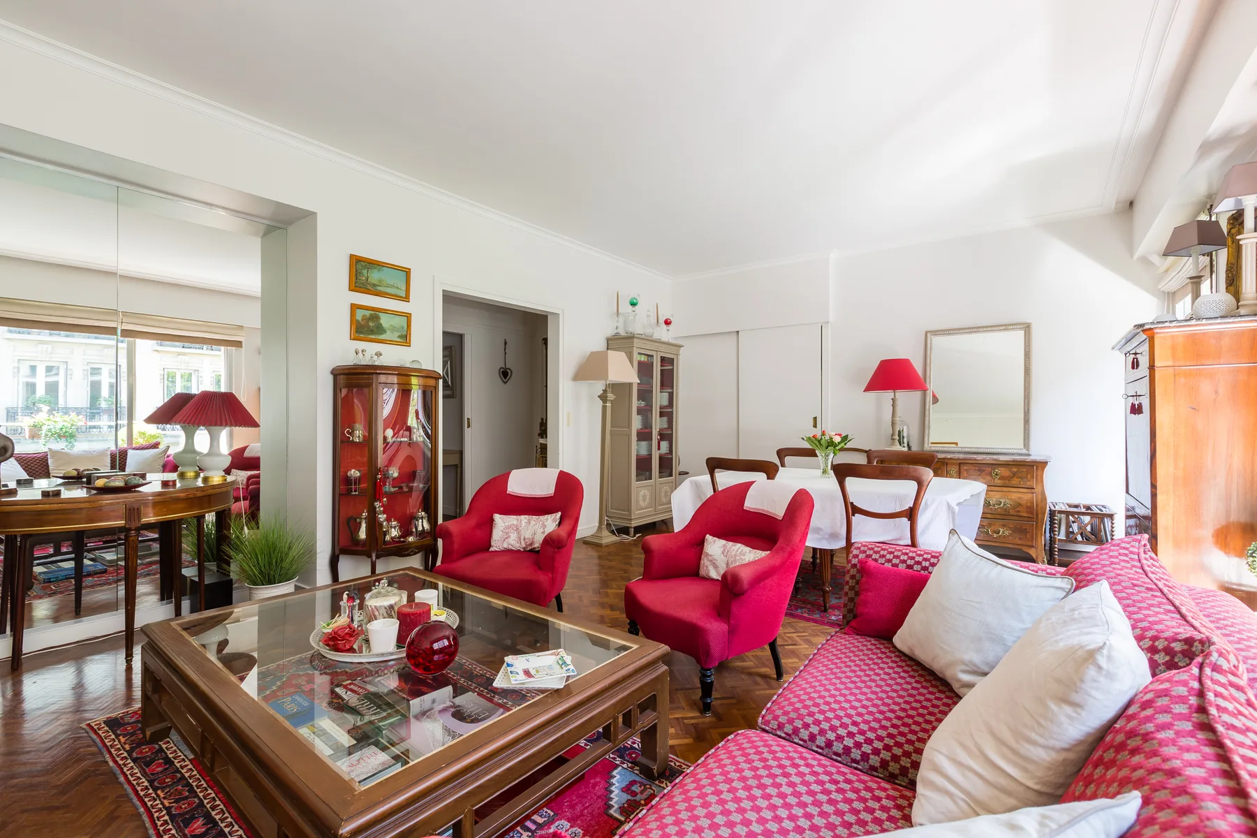 Una sala luminosa con asientos rojos y una mesa de centro con tapa de vidrio.