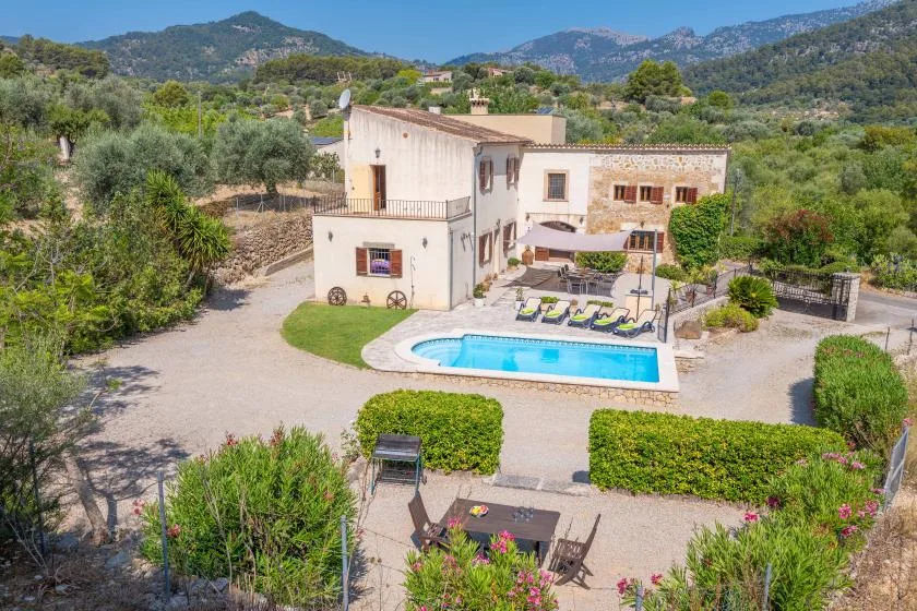 Una casa rural con piscina al aire libre y colinas alrededor.