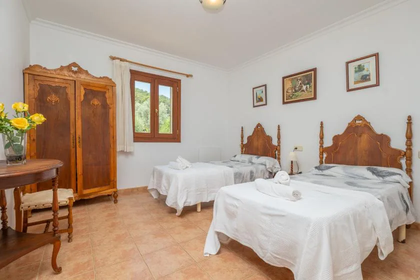 Un dormitorio luminoso con varias camas vestidas de blanco y muebles de madera.