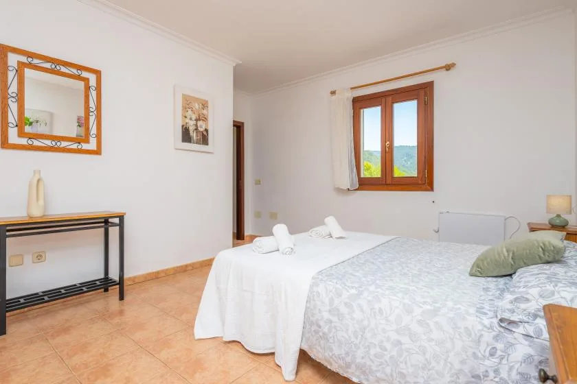 Un dormitorio luminoso con una cama y una ventana con marco de madera.