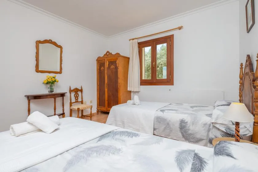 Un dormitorio con varias camas, un armario de madera y una ventana.