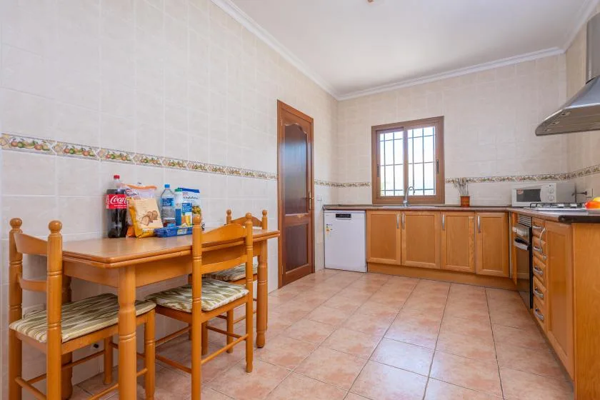 Una cocina con armarios de madera, una mesa de comedor y una ventana.