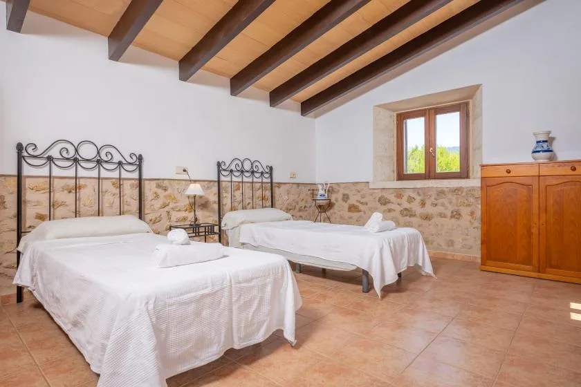 Un dormitorio con dos camas, vigas de techo vistas y una ventana.