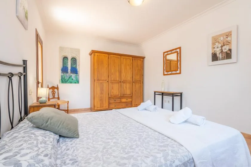 Un dormitorio con dos camas, un armario de madera y cuadros enmarcados.