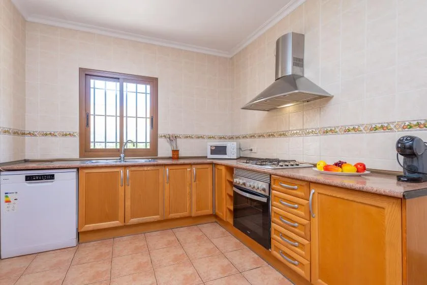 Una cocina con azulejos, armarios de madera, una ventana y una estufa.
