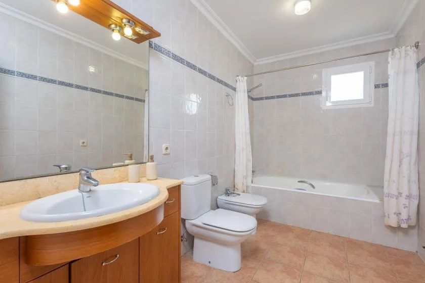 Un baño alicatado con lavabo, inodoro y bañera.