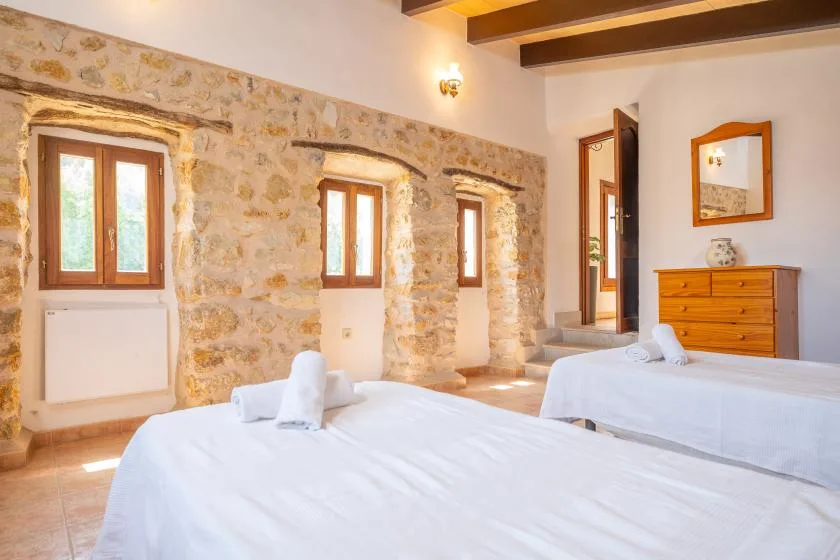 Un dormitorio con dos camas y ventanas en una pared de piedra.