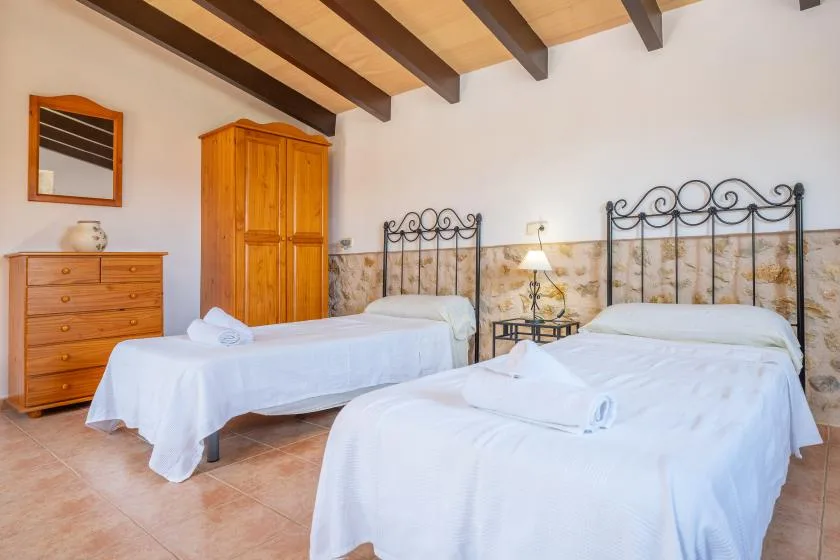 Un dormitorio con dos camas, muebles de madera y vigas vistas en el techo.