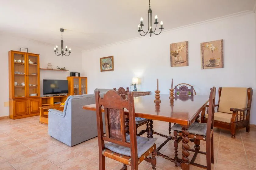 Un comedor y sala de estar con una mesa de madera, sillas y un televisor.