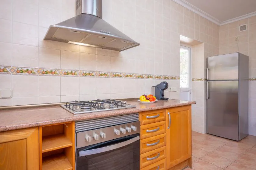 Una cocina alicatada con una estufa sobre la encimera y un refrigerador de acero inoxidable.