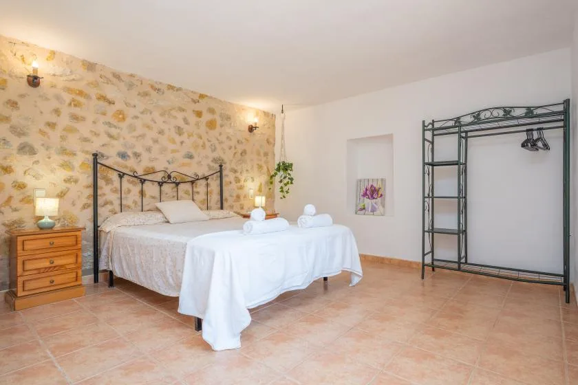 Un dormitorio con una cama, una mesita de noche y un perchero abierto.