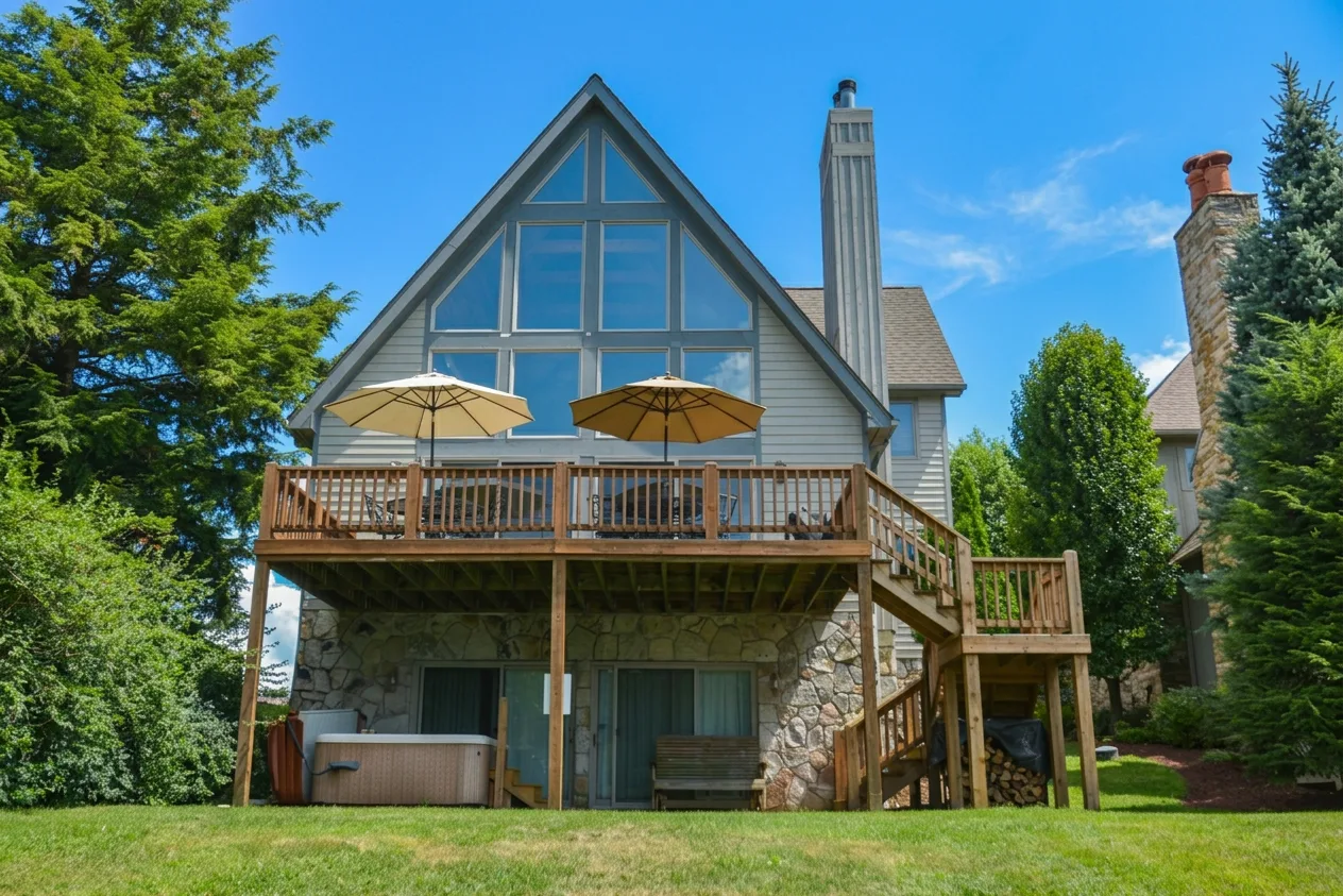 A large house with a raised wooden deck and outdoor umbrellas.