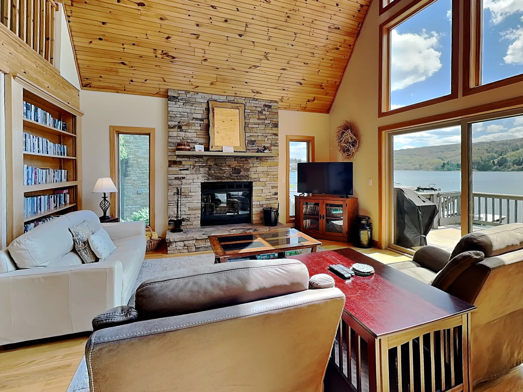 A living room with seating arranged around a fireplace and large windows overlooking the water.