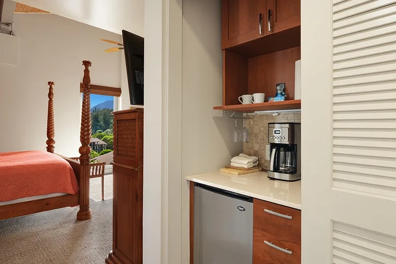 A bedroom with a bed beside a built-in coffee station.