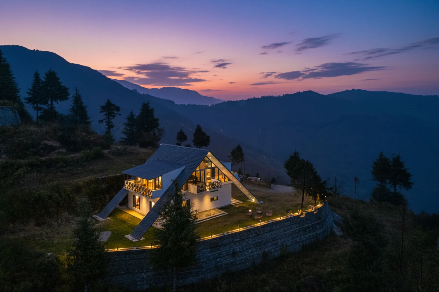Una casa moderna se ilumina en una ladera bajo un cielo colorido al atardecer.