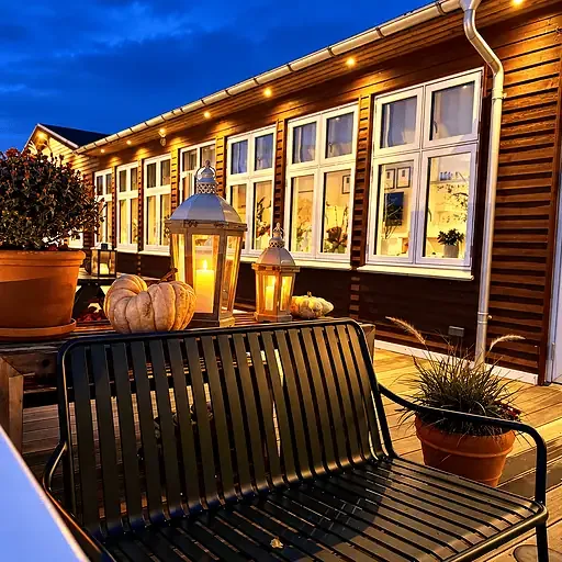Terraza exterior del Knudhule Badehotel iluminada al anochecer.