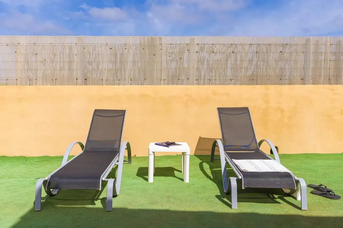 A sunny outdoor seating area with two loungers and a small table.