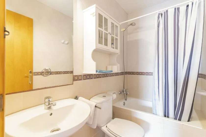 A bathroom with a sink, toilet, and bathtub behind a striped shower curtain.