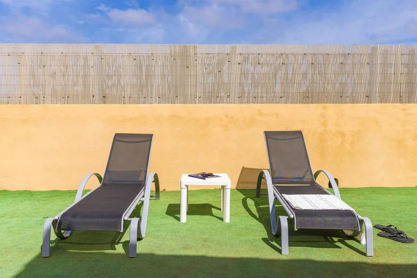 Outdoor seating area with two loungers and a small table on green turf.
