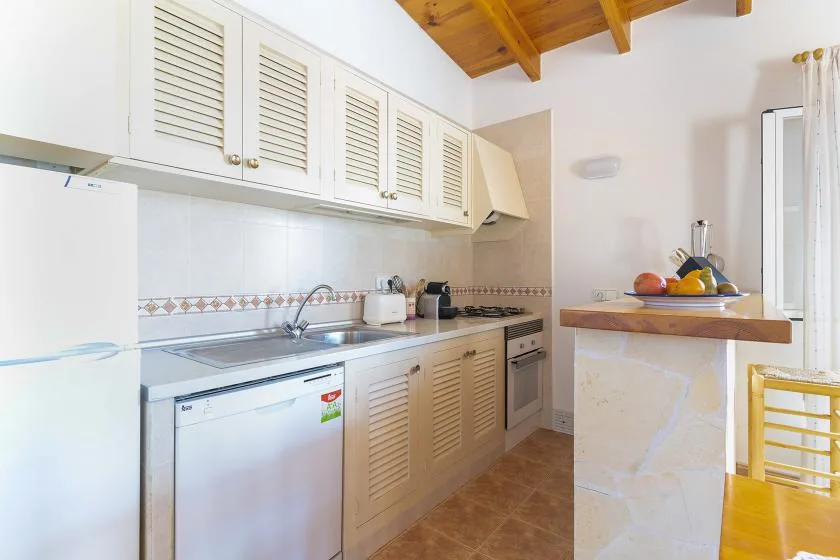 A compact kitchen with white cabinets, a sink, and a breakfast counter.