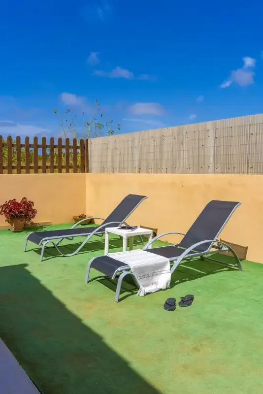 A sunny outdoor patio with reclining loungers and a small table.