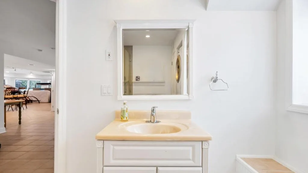 A bathroom vanity with a sink sits beneath a wall mirror.