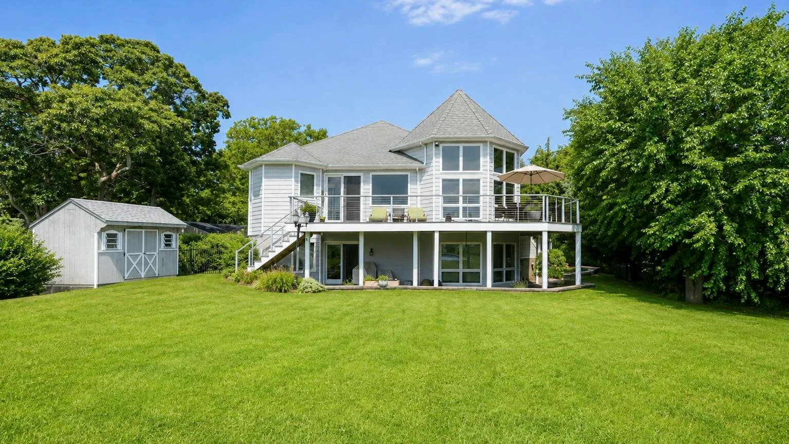 A large house with a broad green lawn and a small shed nearby.