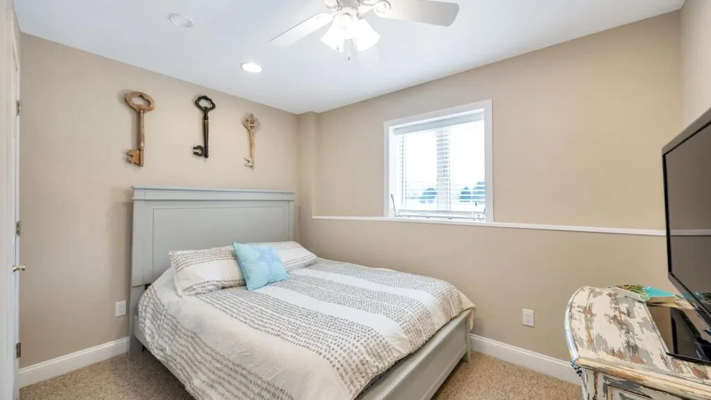 A bedroom with a bed, a window, and a ceiling fan.