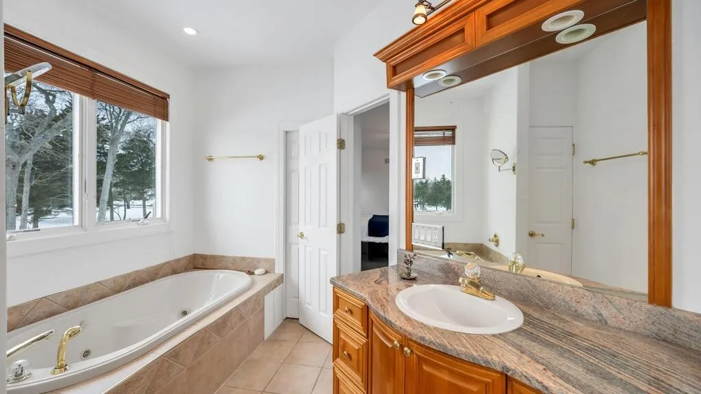 A bathroom with a bathtub and a wood-trimmed vanity.