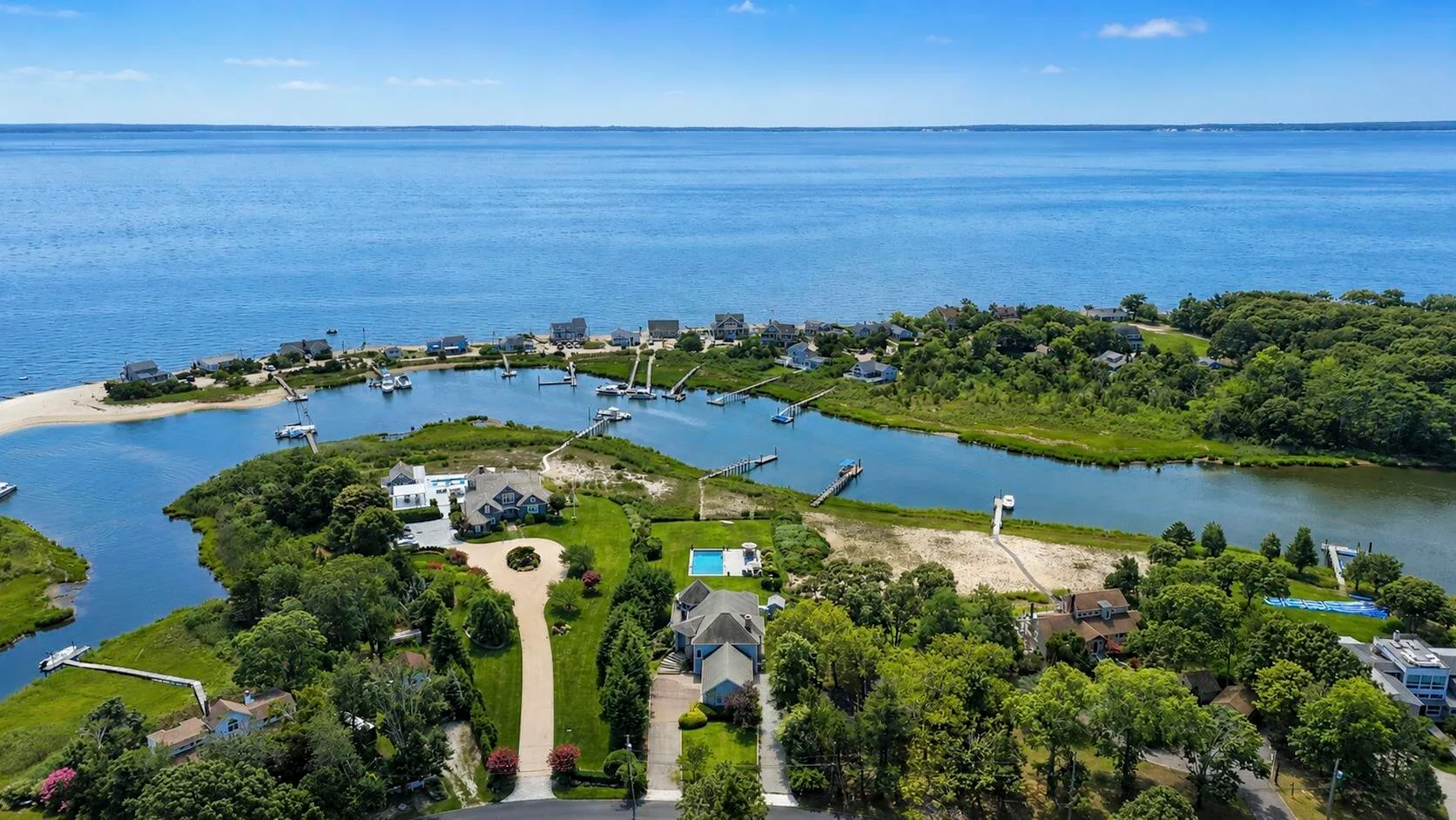 Aerial view of a coastal neighborhood with homes, greenery, and water.