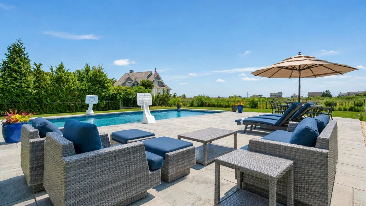 An outdoor poolside seating area with lounge chairs and a large umbrella.