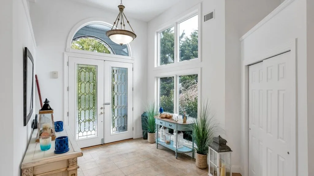 A bright entryway with glass-paneled doors and tall windows.